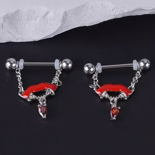 Close up of vampire lips nipple jewelry on a dark textured surface