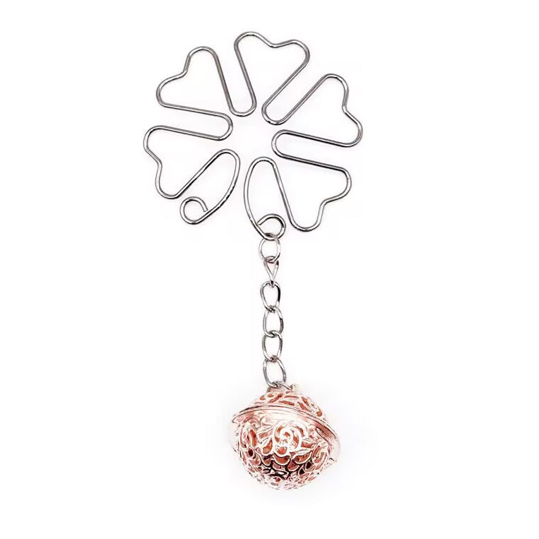 Single silver flower shaped non-pierced clip with a rose gold filigree bell dangle on white background.