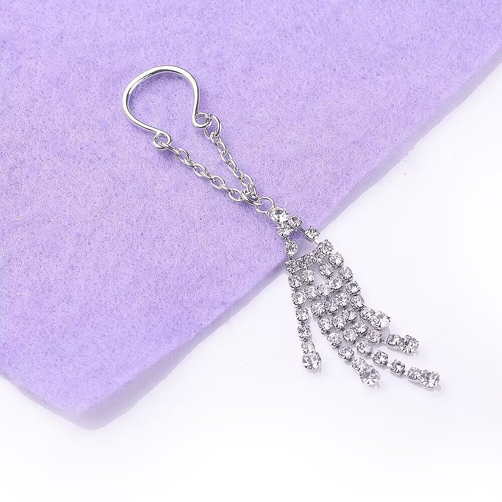 Close-up flat lay of crystal fringe body jewelry on purple fabric.