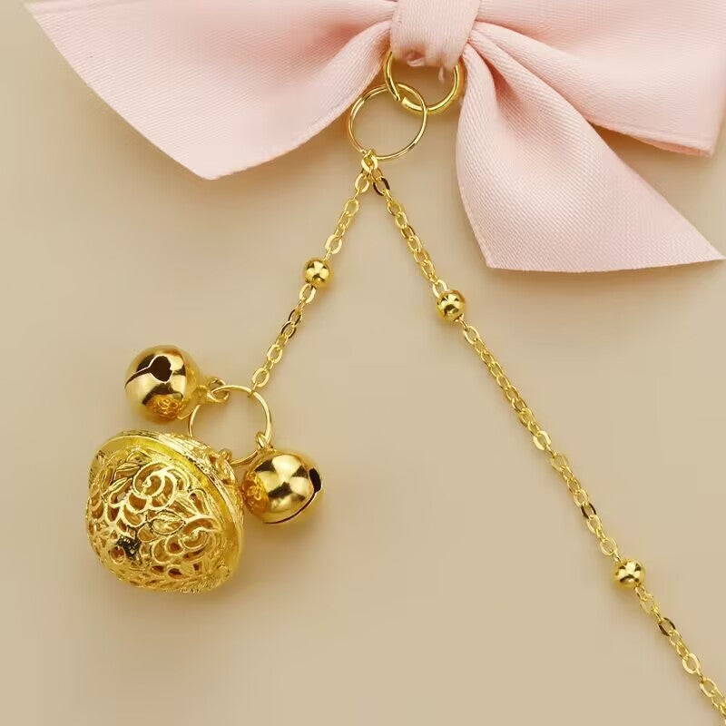 Close-up of a delicate golden filigree bell and beaded chain attachment.