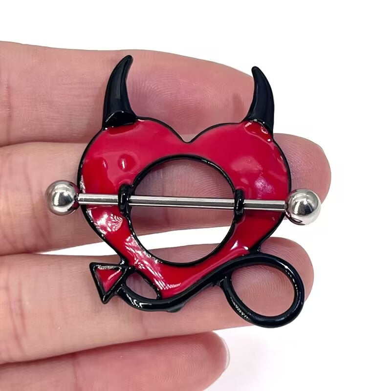 Hand holding a red and black Gothic Devil Heart nipple shield to show scale and texture.