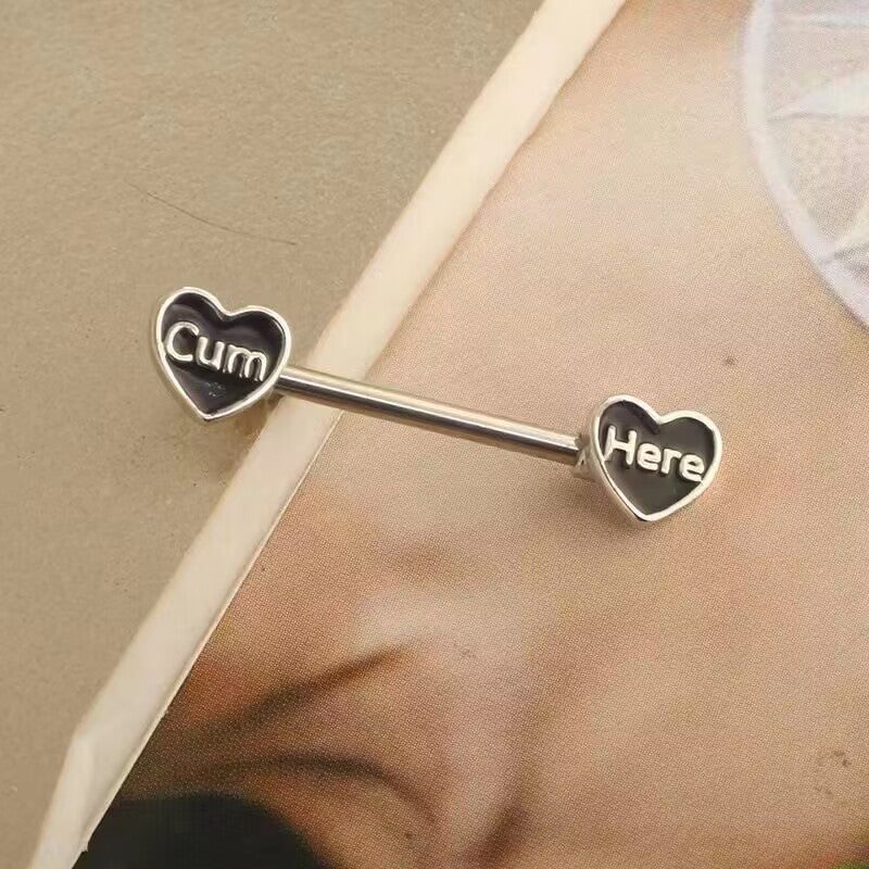 Close-up shot of a black heart nipple ring resting on a skin-toned background.