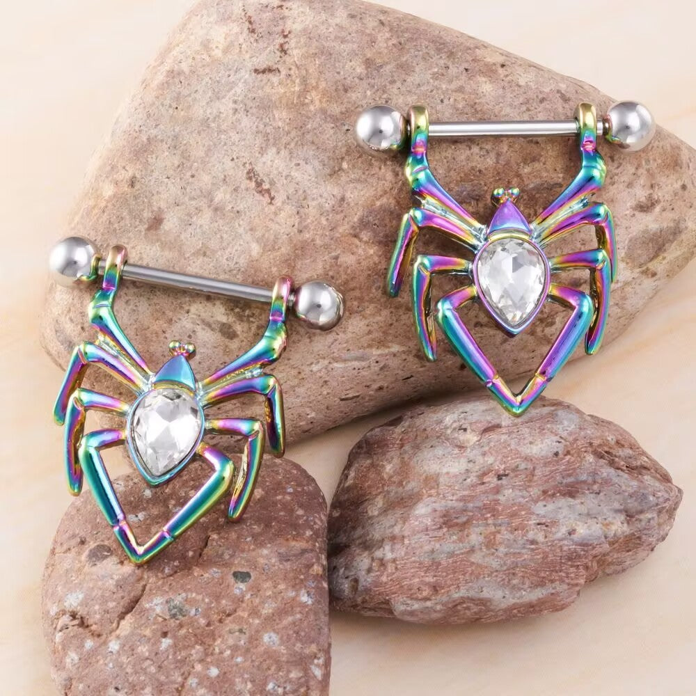 A pair of iridescent rainbow anodized spider nipple piercing shields with clear white gems.