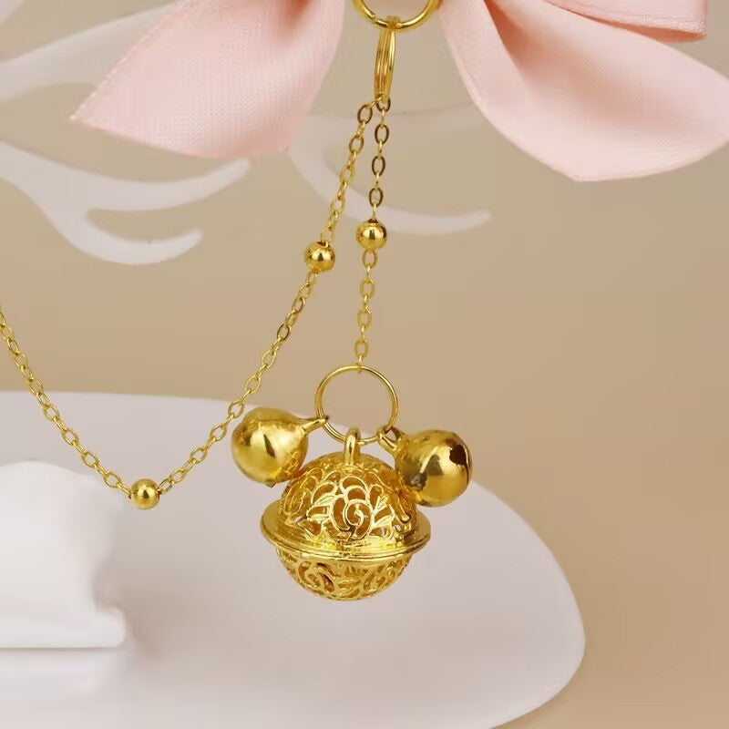 Macro view of the ornate bell pendant and fine link chain.