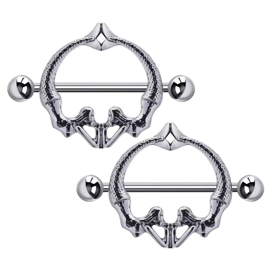 A pair of skeleton-style nipple shield jewelry showing the intricate bone and tail design.