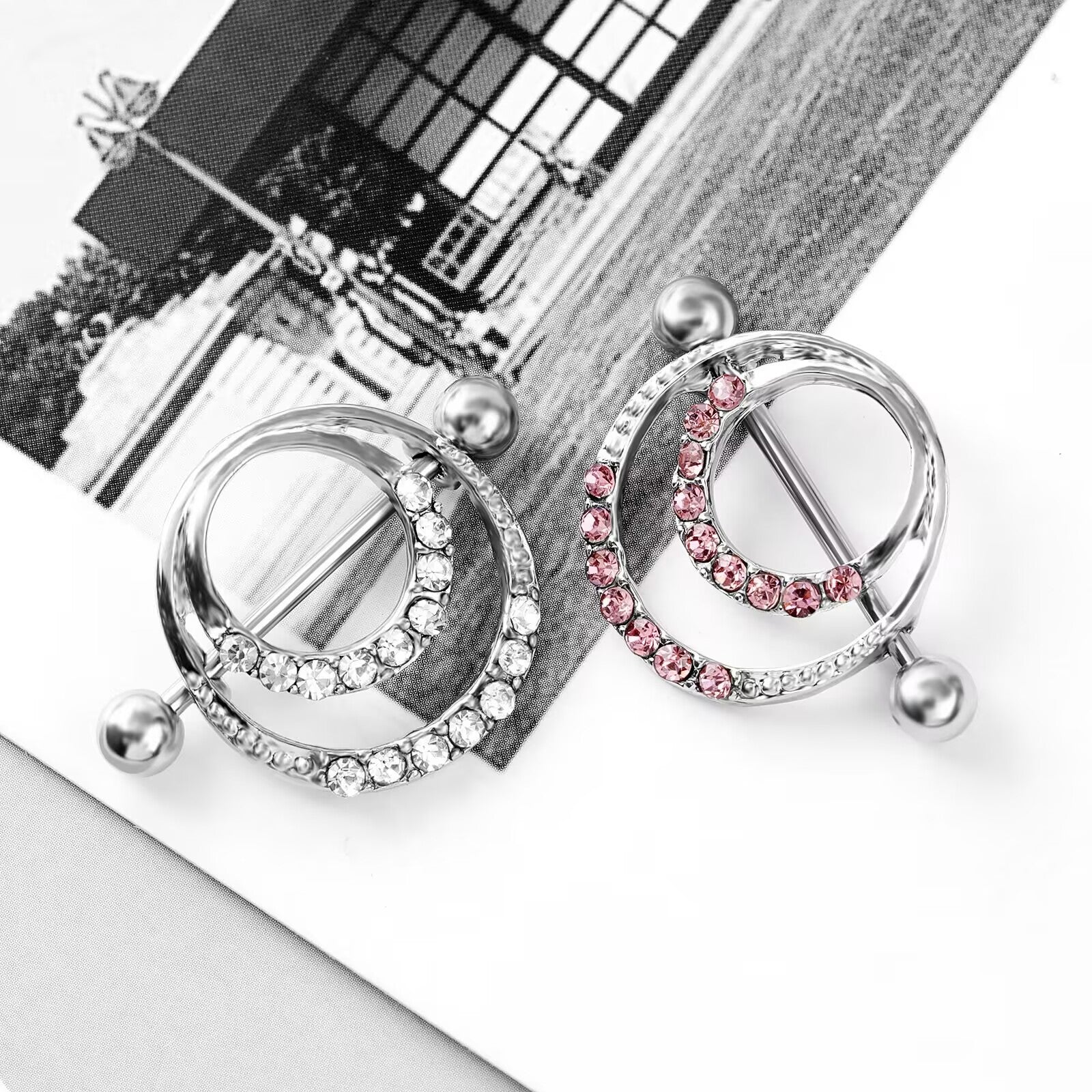 Artistic arrangement of pink and white crystal nipple piercing rings.