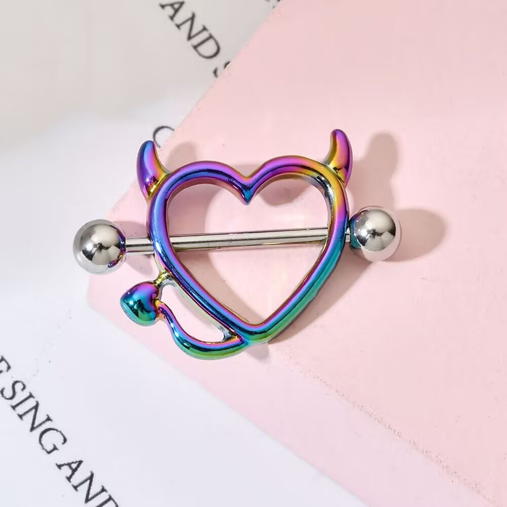 Close up of rainbow devil heart nipple shield on pink background