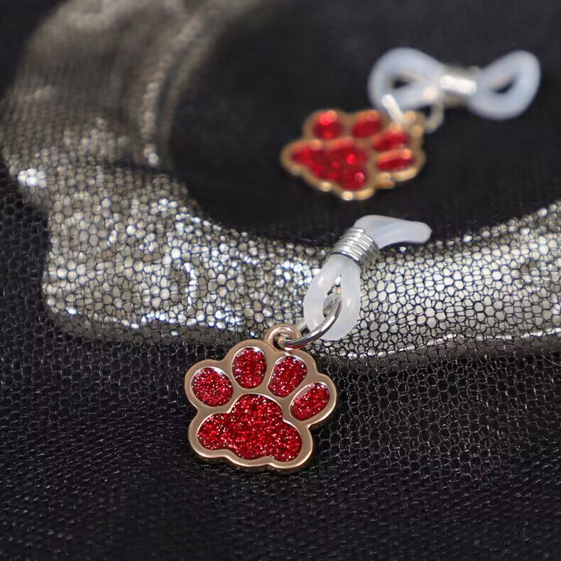 Red sparkling paw print accessory lying on a decorative mesh surface.