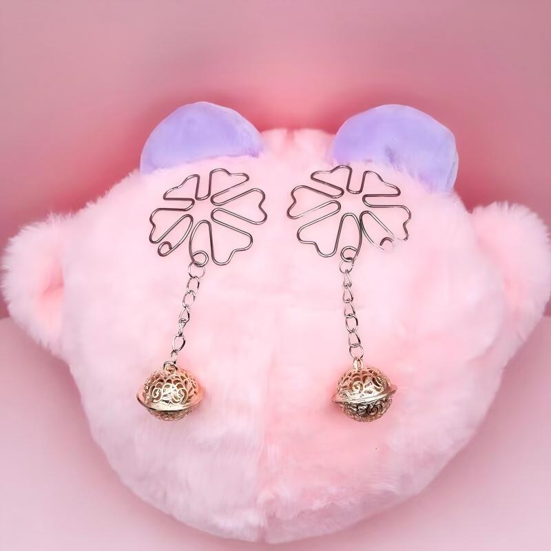 Rose gold filigree bell dangle clips placed on a soft pink background for feminine marketing.