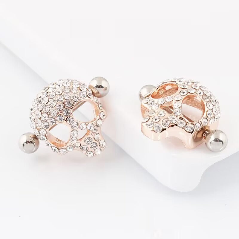 Two rose-gold skull nipple shields shown together on a white background, one front and one profile view.