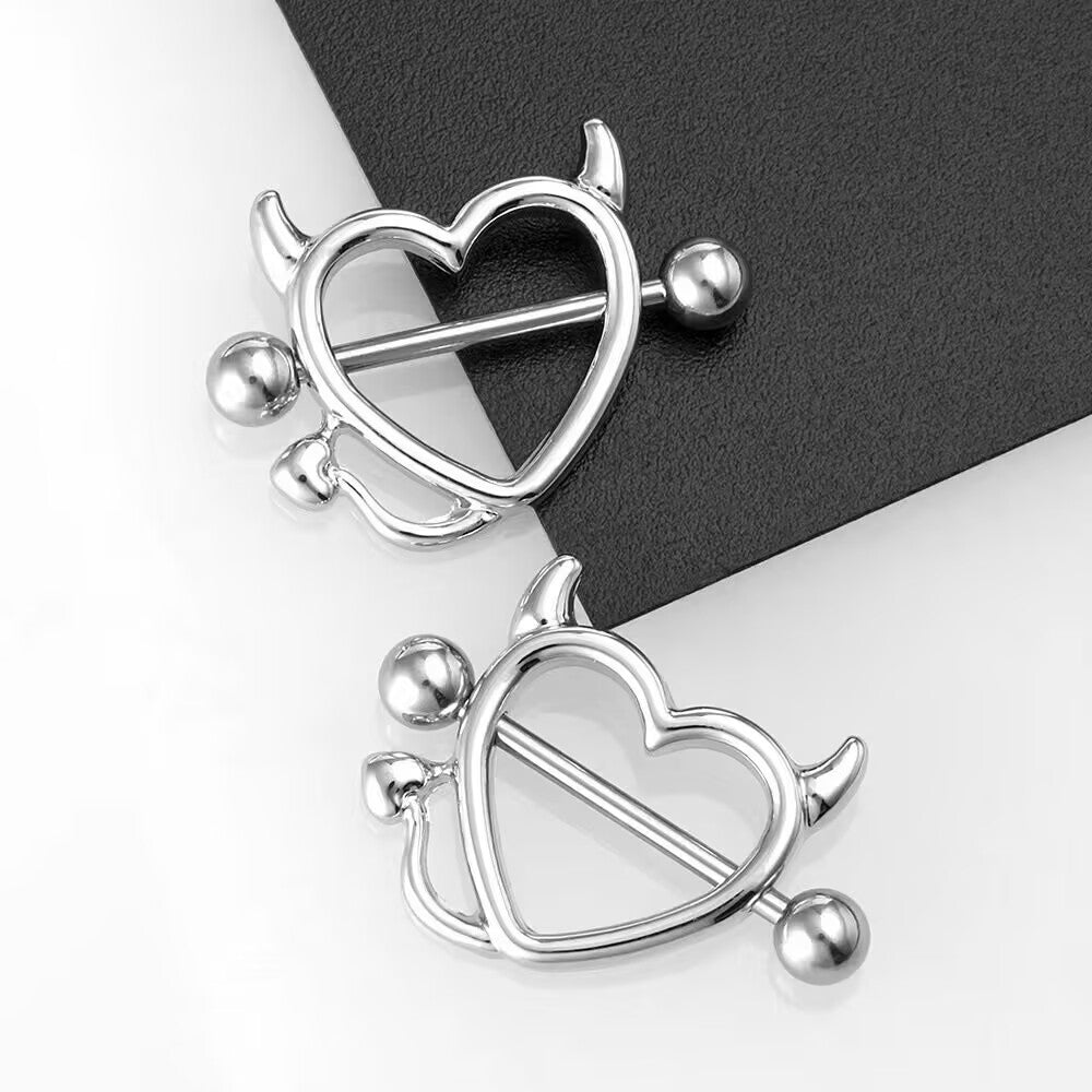 Two silver heart-shaped nipple shields with demon aesthetic