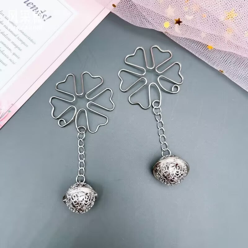 Flatlay of silver floral body jewelry next to a decorative card on a grey background.