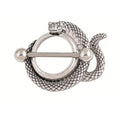 Front view of an antique silver snake nipple shield with a coiled serpent design.