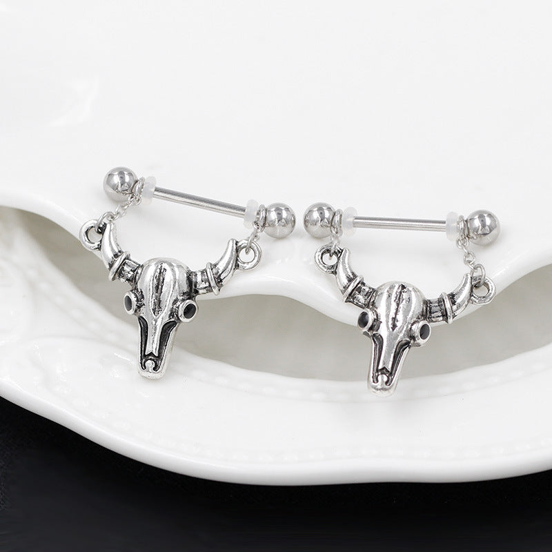 Front view of bull skull nipple piercing jewelry with black eye accents on a white decorative plate.